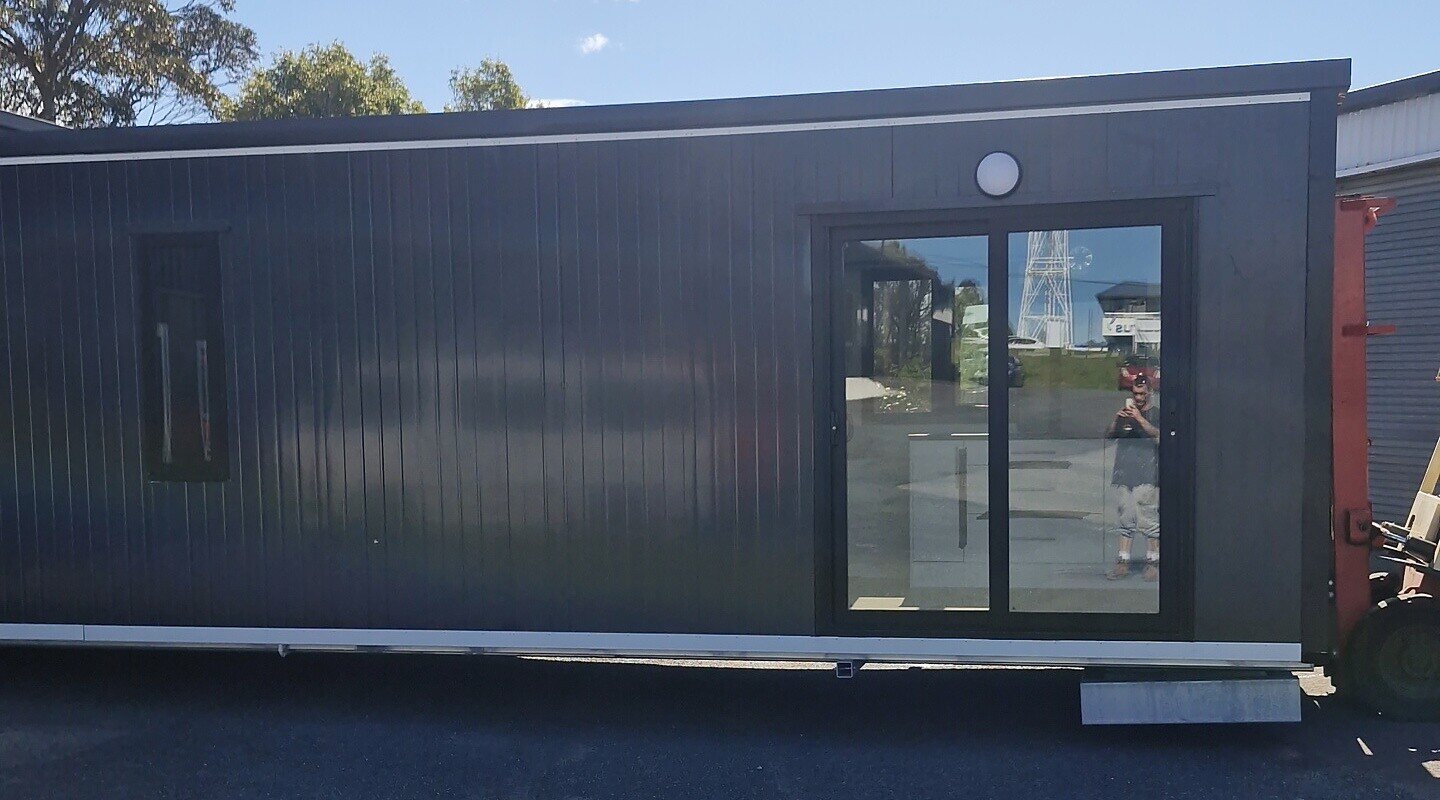 A 10 × 3 m charcoal Simple Cabins cabin with a ranch slider, a similar build one metre longer