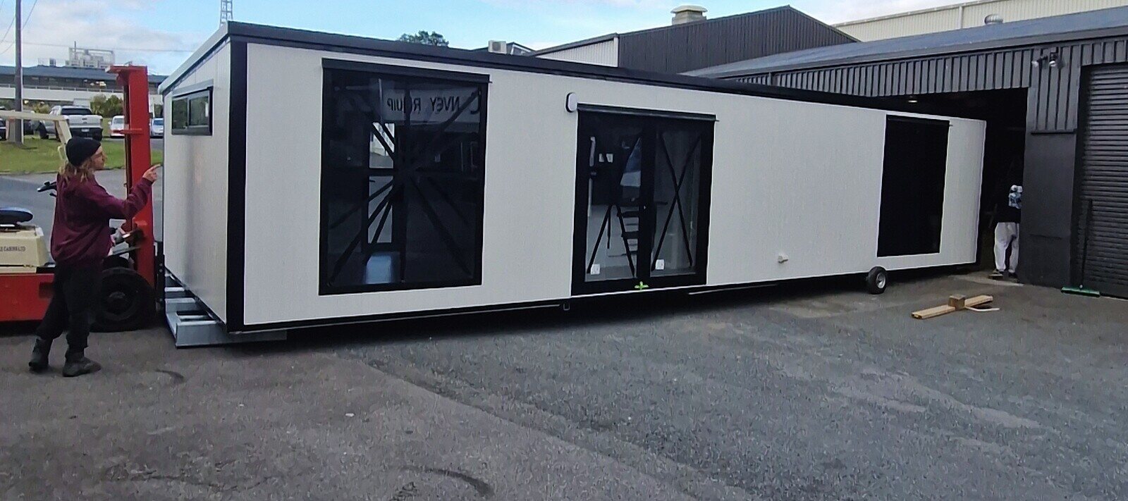 The white 12 × 4 m Simple Cabins cabin with large black joinery, in the Bell Block yard
