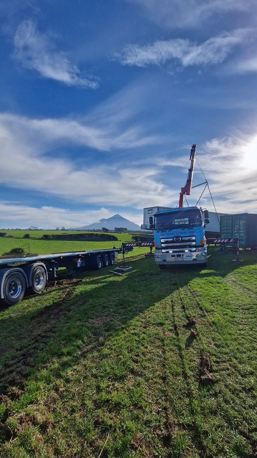 A finished Simple Cabins cabin on the truck, crossing a Taranaki paddock on its way to site