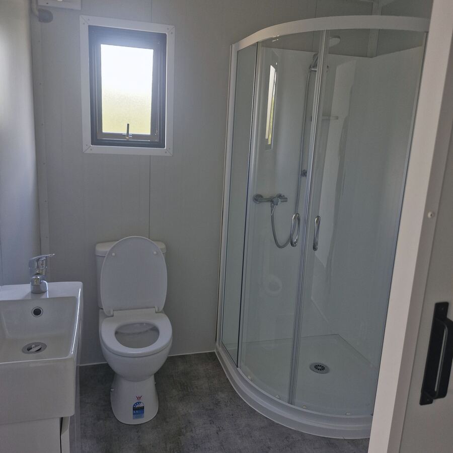 A cabin bathroom with a corner shower, toilet and vanity
