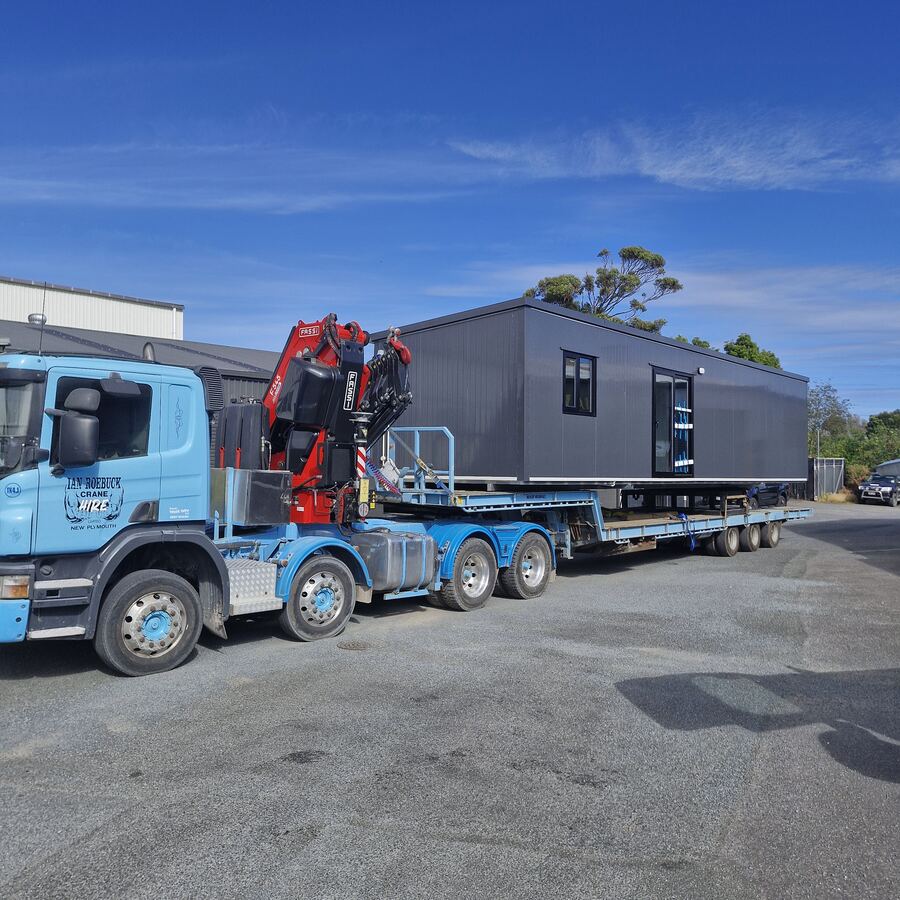 A cabin loaded on a hiab truck and trailer, ready for delivery