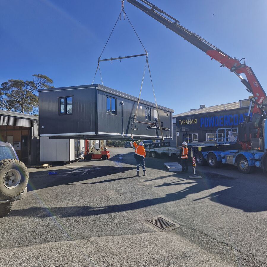 A finished cabin being lifted off the truck by Hiab in the Bell Block yard