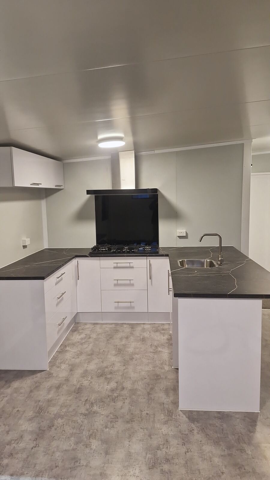 A fitted cabin kitchen with white cabinets, a dark benchtop and an oven
