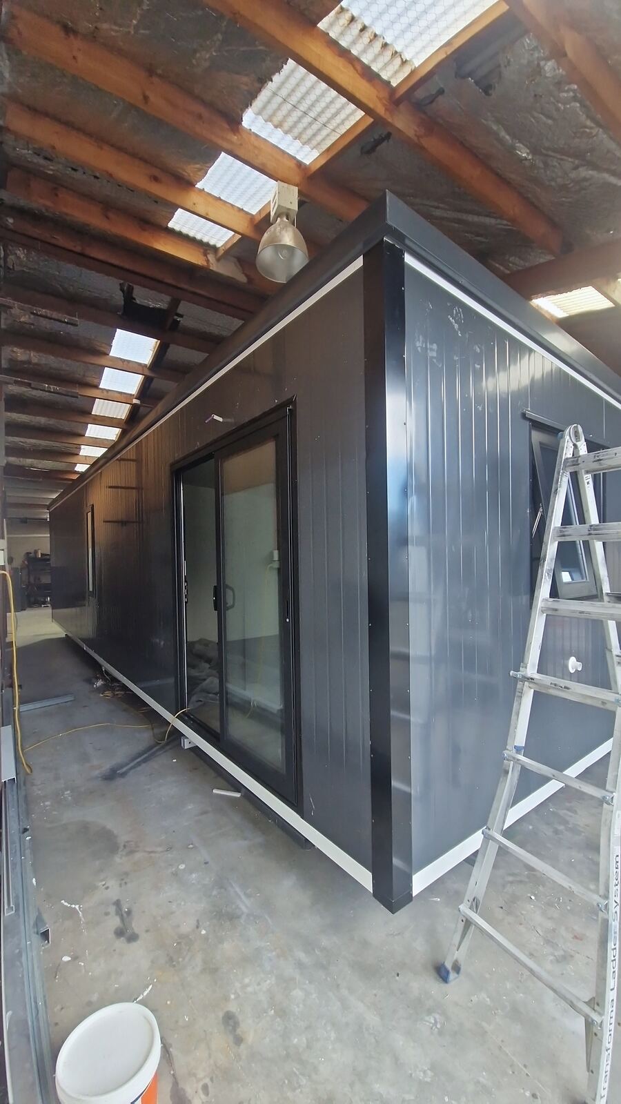 A 10 × 3 m charcoal cabin with a ranch slider, in the workshop